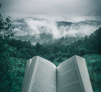 book-open-in-front-of-mountains-and-forests